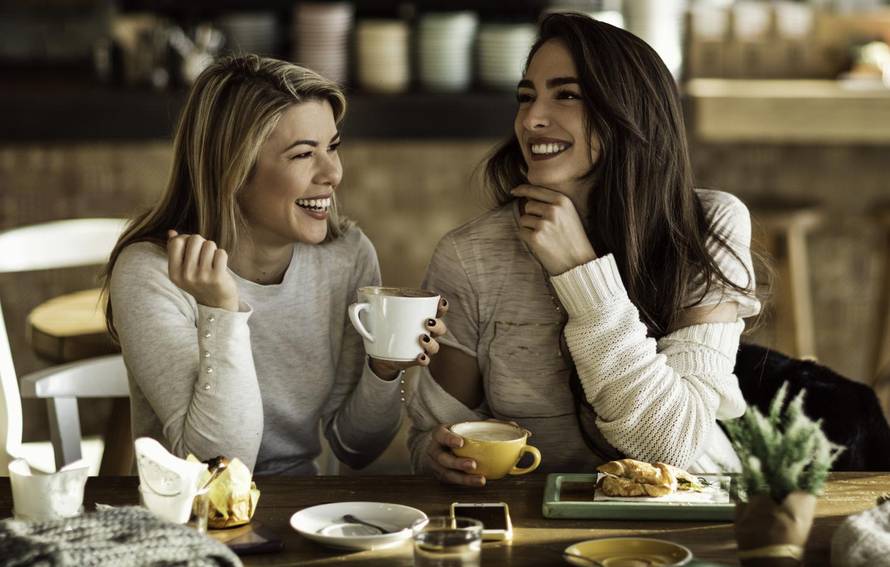 Two cheerful women having fun during coffee time in a cafe.