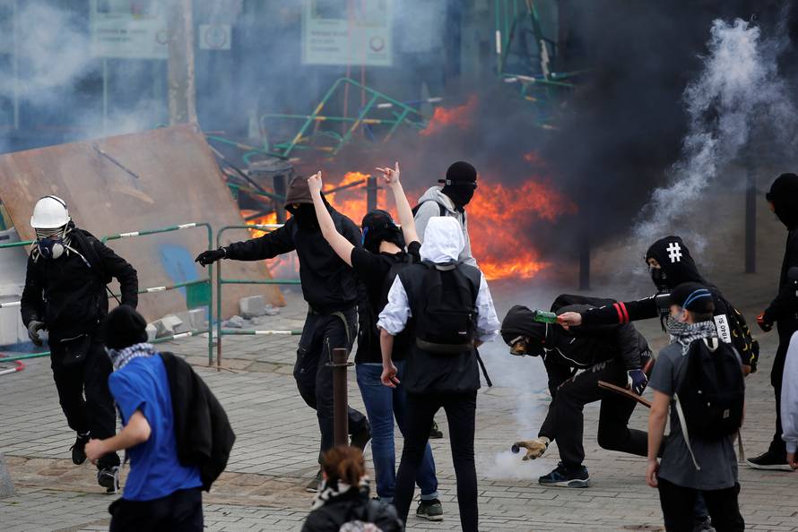 Youths take cover from tear gas during clashes during a demonstration against the French labour law proposal in Nantes