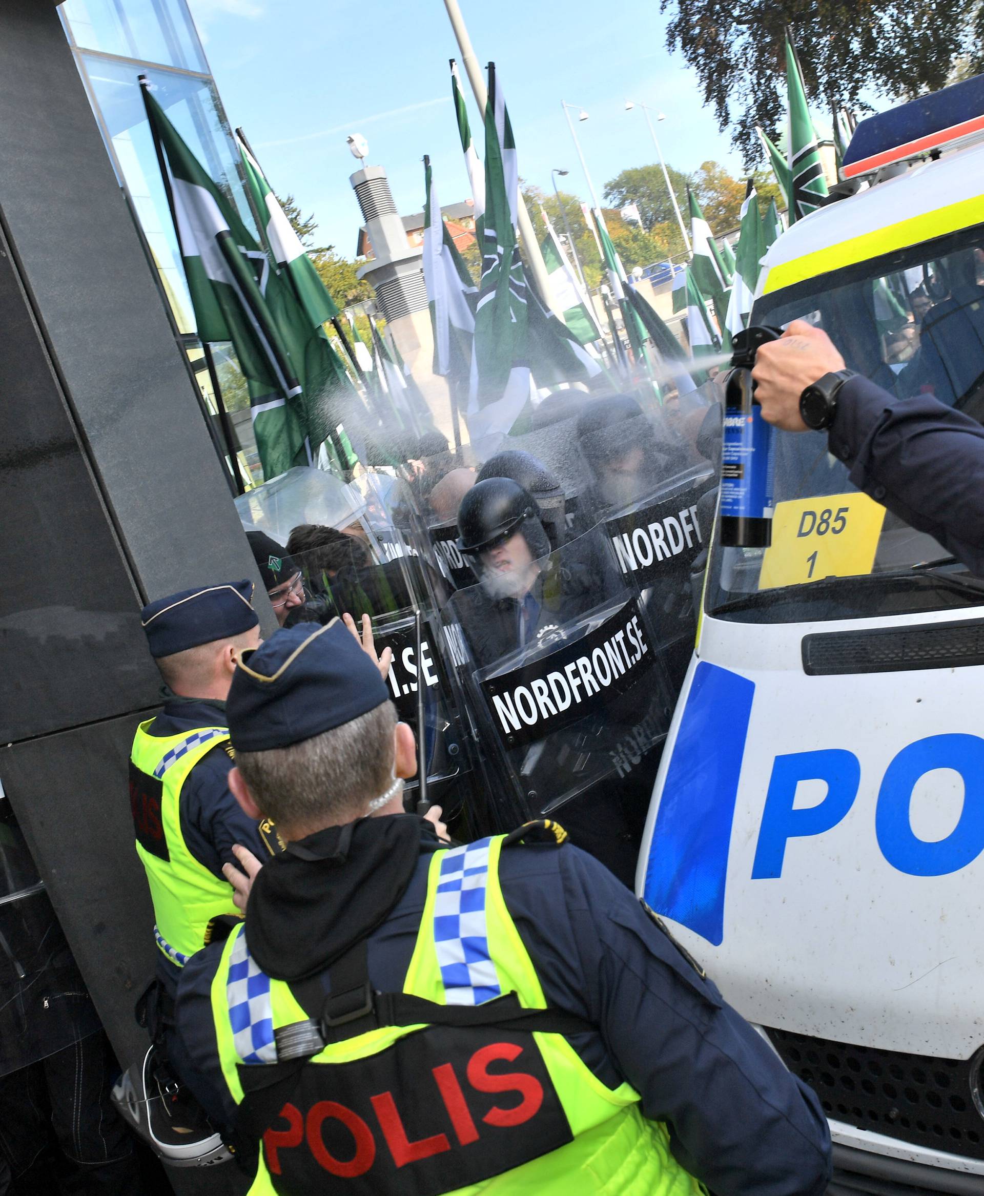 A police officer uses pepper spray on NMR demonstrators as they try to walk along a forbidden street during the Nordic Resistance Movement march in central Gothenburg