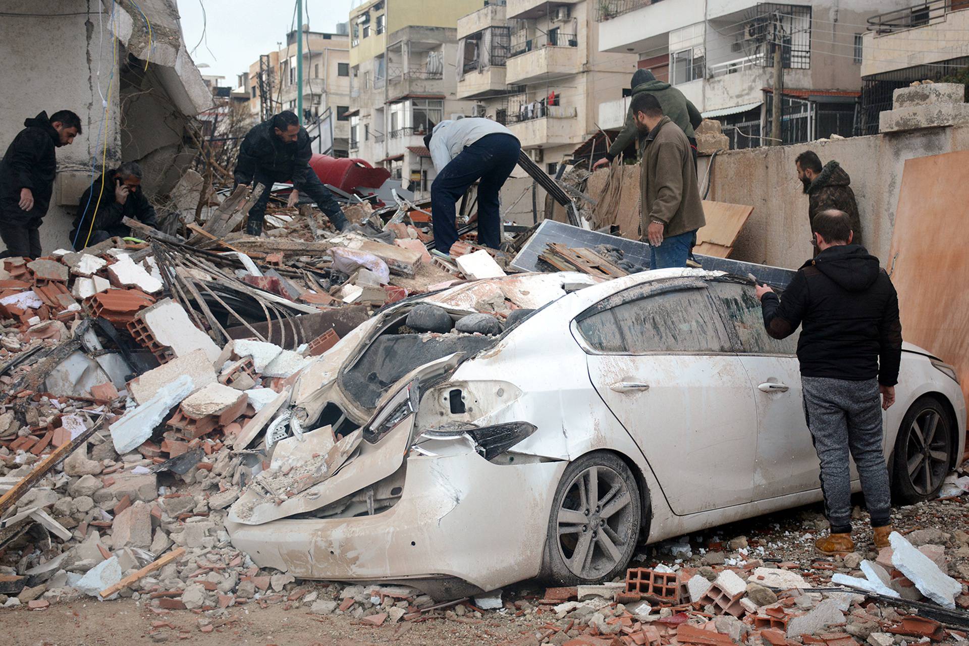 Rescuers search for survivors at the site of a collapsed building, following an earthquake, in Latakia