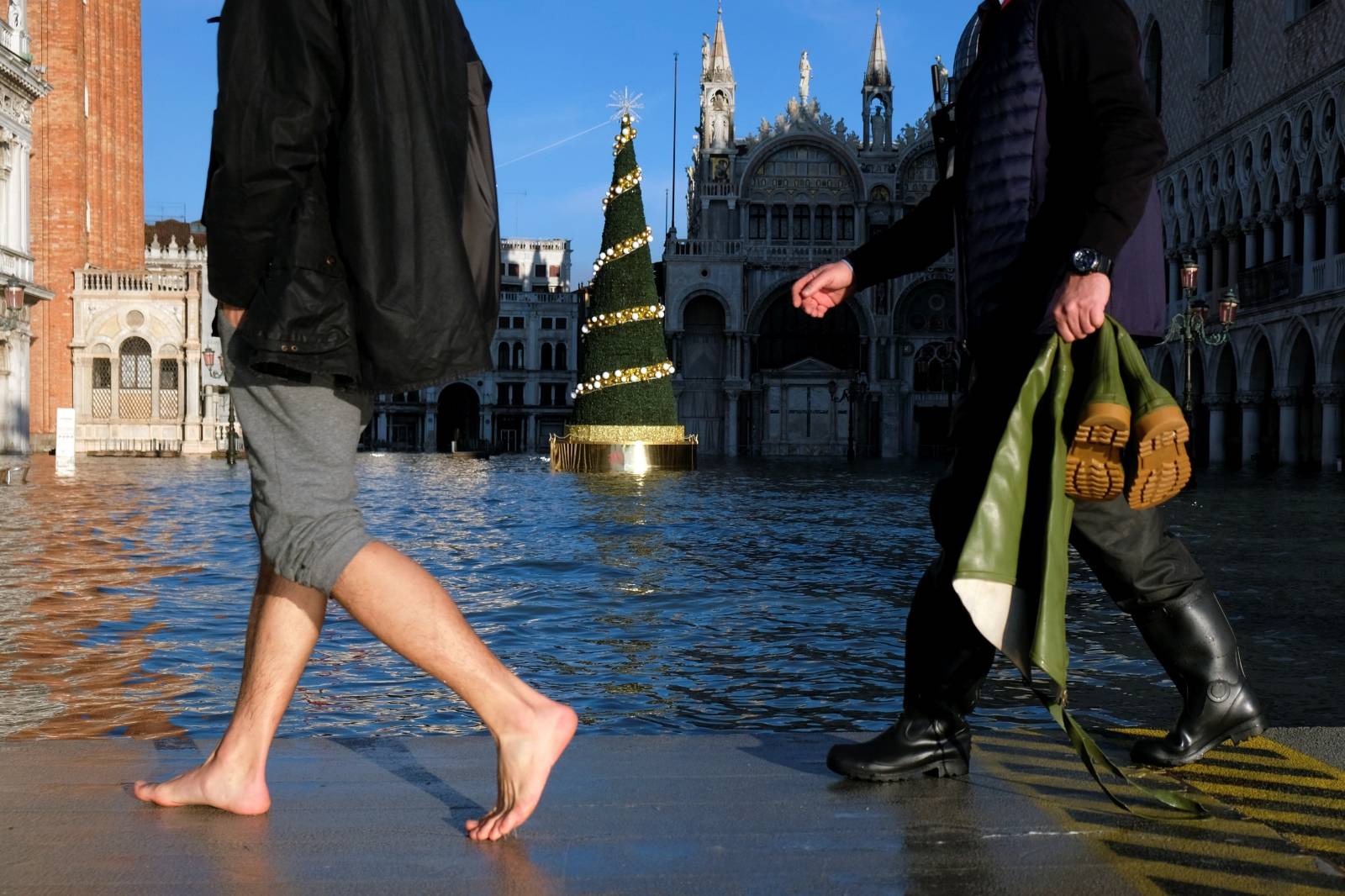 People walk in St. Mark’s Square during high tide in Venice