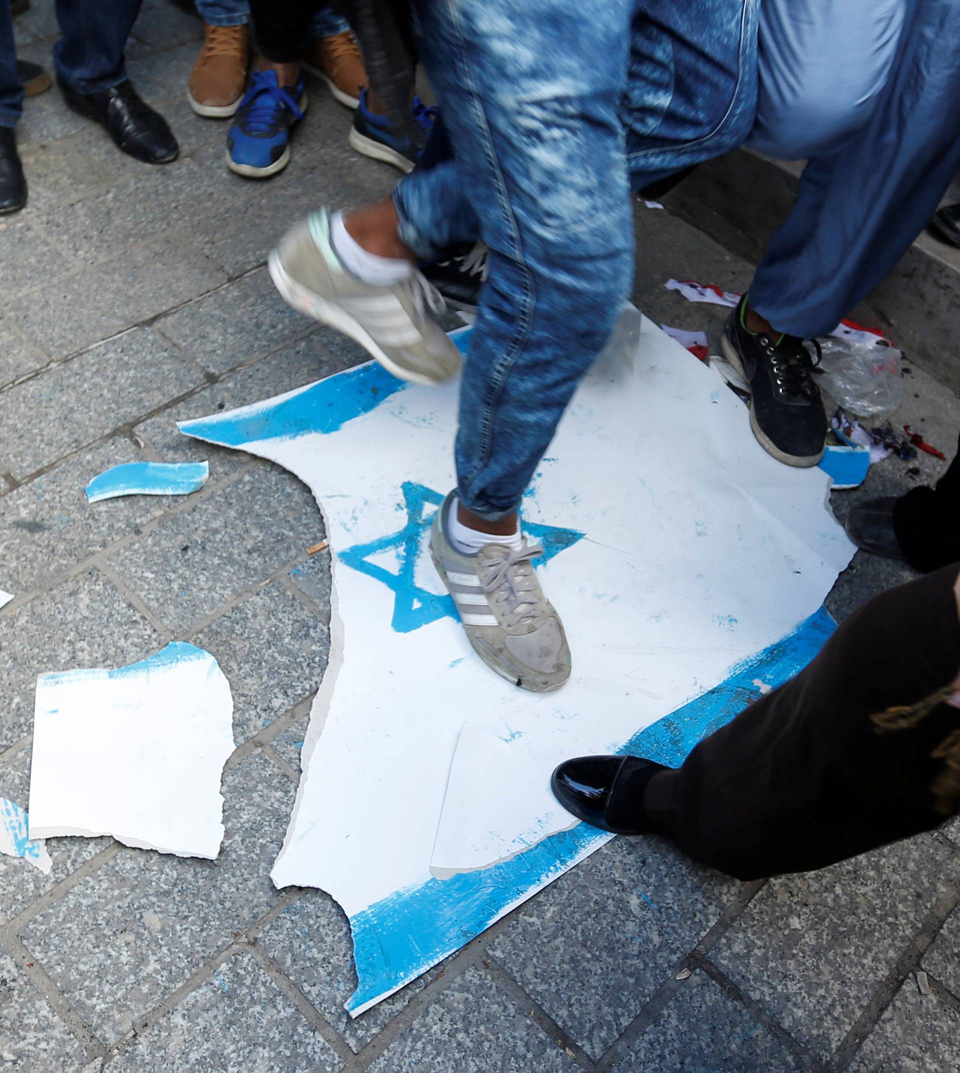 People step on an Israeli flag during a protest against U.S. President Donald Trump's decision to recognise Jerusalem as the capital of Israel, in Tunis