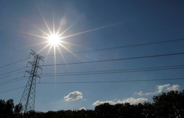 FILE PHOTO: Sun shines over a high tension power line in an industrial area of Sydney