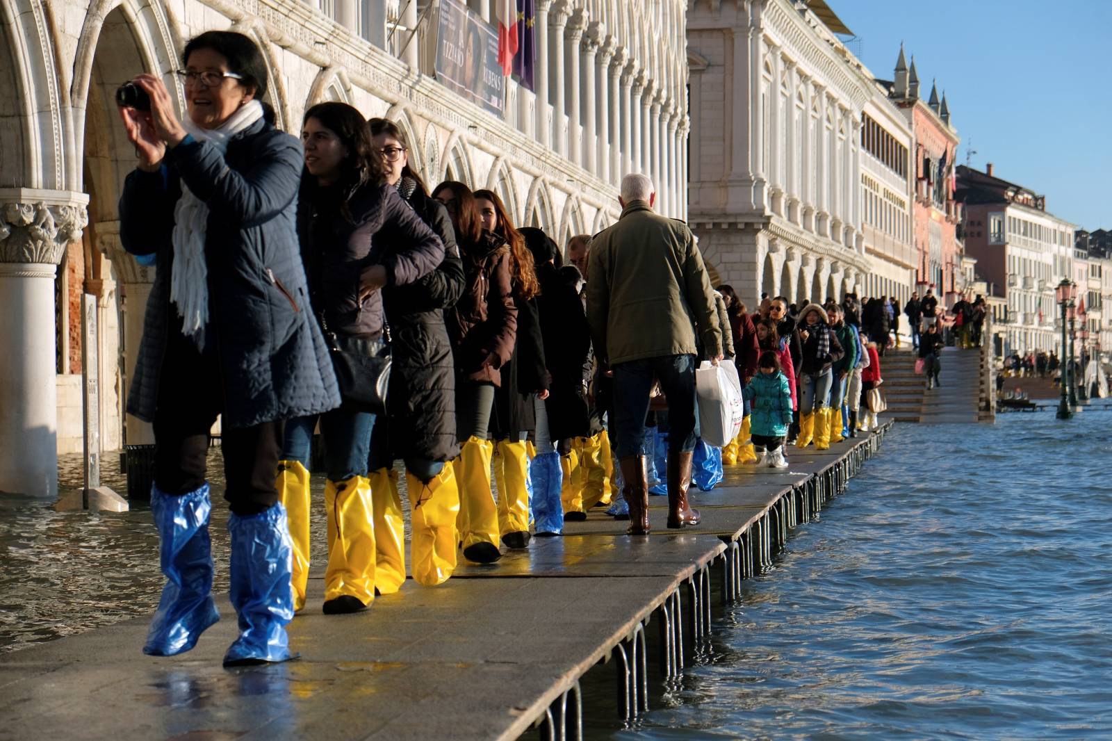Tourists walk in St. Mark’s Square during high tide in Venice