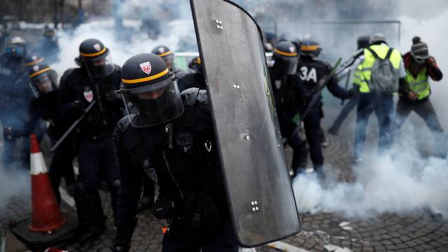 Protesters wearing yellow vest, a symbol of a French drivers' protest against higher fuel prices, clash with riot police on the the Champs-Elysee in Paris