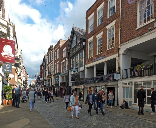 people walking along watergate street past pubs and shops in chester