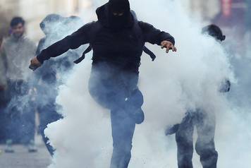 Demonstrators react amid tear gas, the day after a national day of demonstrations against the cost of living and rising fuel prices, in Paris
