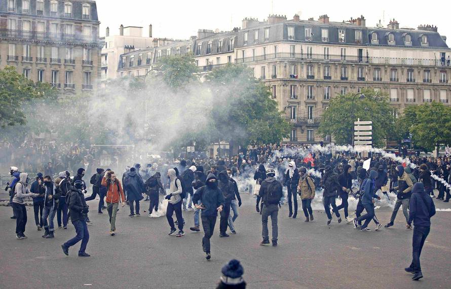 Masked youths run among tear gas during a demonstration against the French labour law proposal in Paris