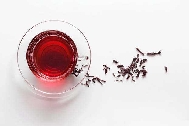 transparent glass cup with Hibiscus tea on the saucer with dry t