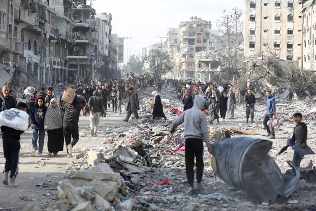 Displaced Palestinians walk past the rubble as they attempt to return to their homes, in the northern Gaza Strip
