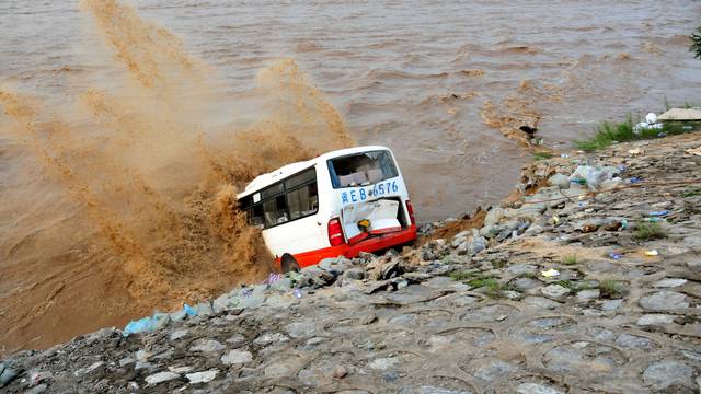 An abandoned bus filled with sand bags is used to build a makeshift dike at a flooded area in Xingtai, Hebei Province