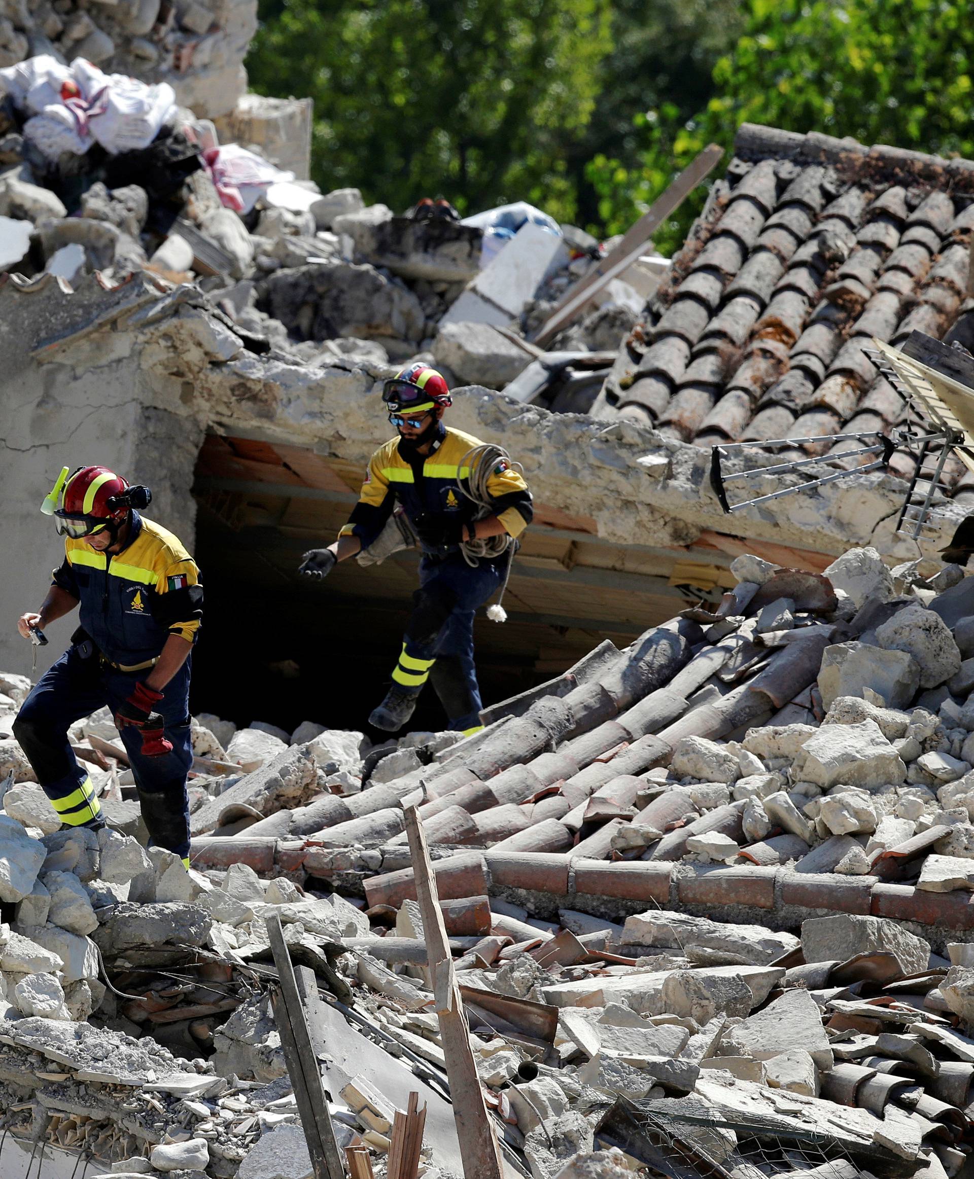 Firefighters inspect damaged houses following an earthquake in Pescara del Tronto