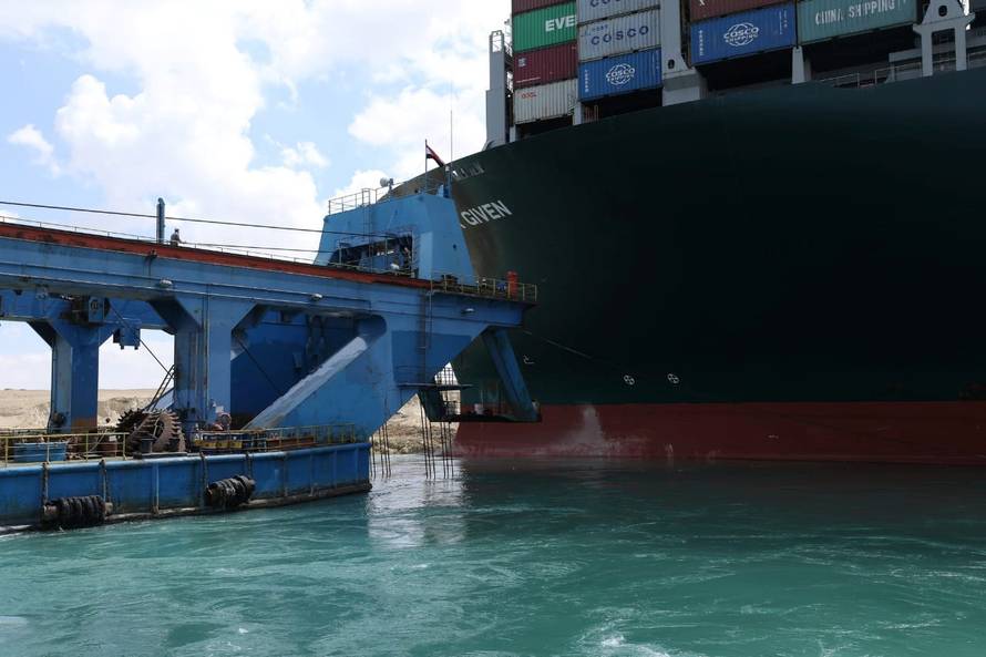 A dredger attempts to free stranded container ship Ever Given, one of the world's largest container ships, after it ran aground, in Suez Canal