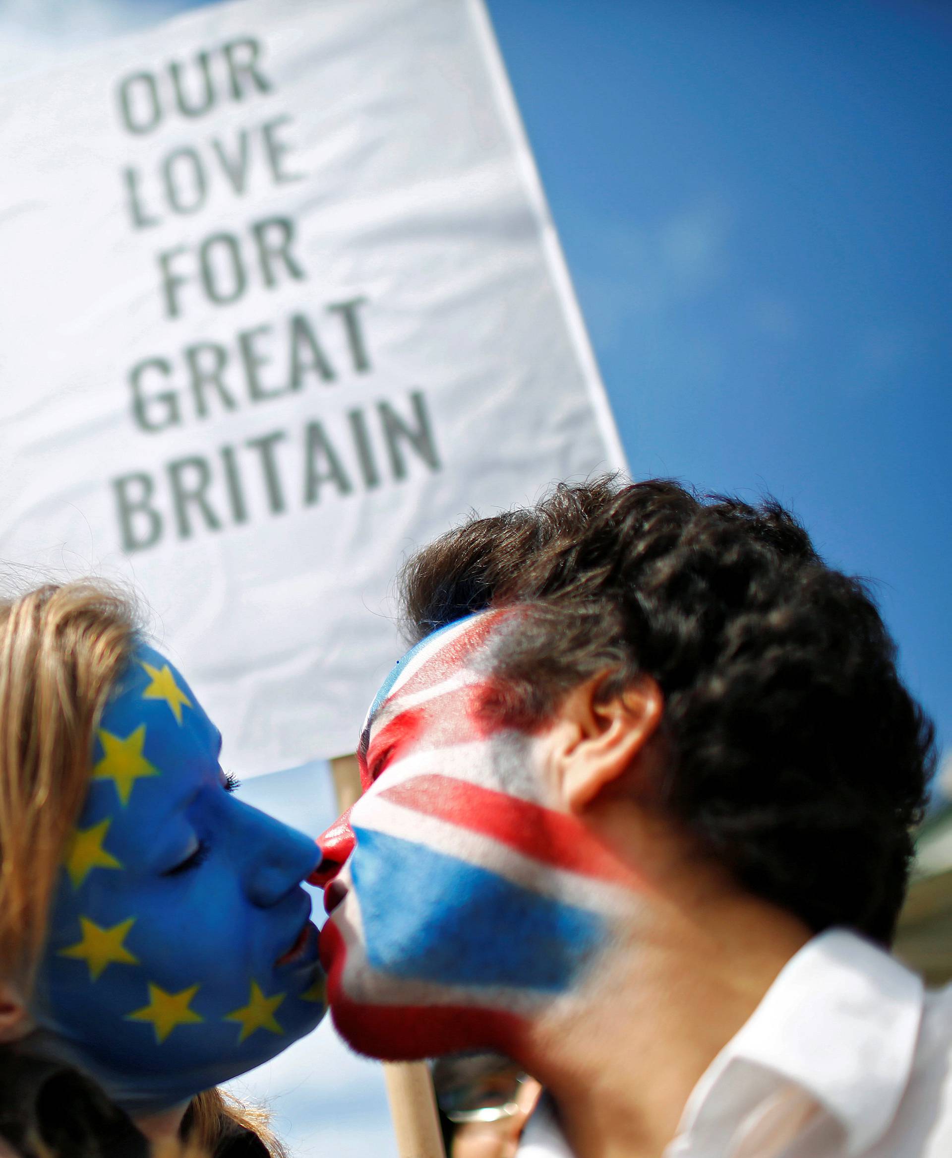 Two activists with the EU flag and Union Jack painted on their faces kiss each other in front of Brandenburg Gate to protest against Brexit in Berlin