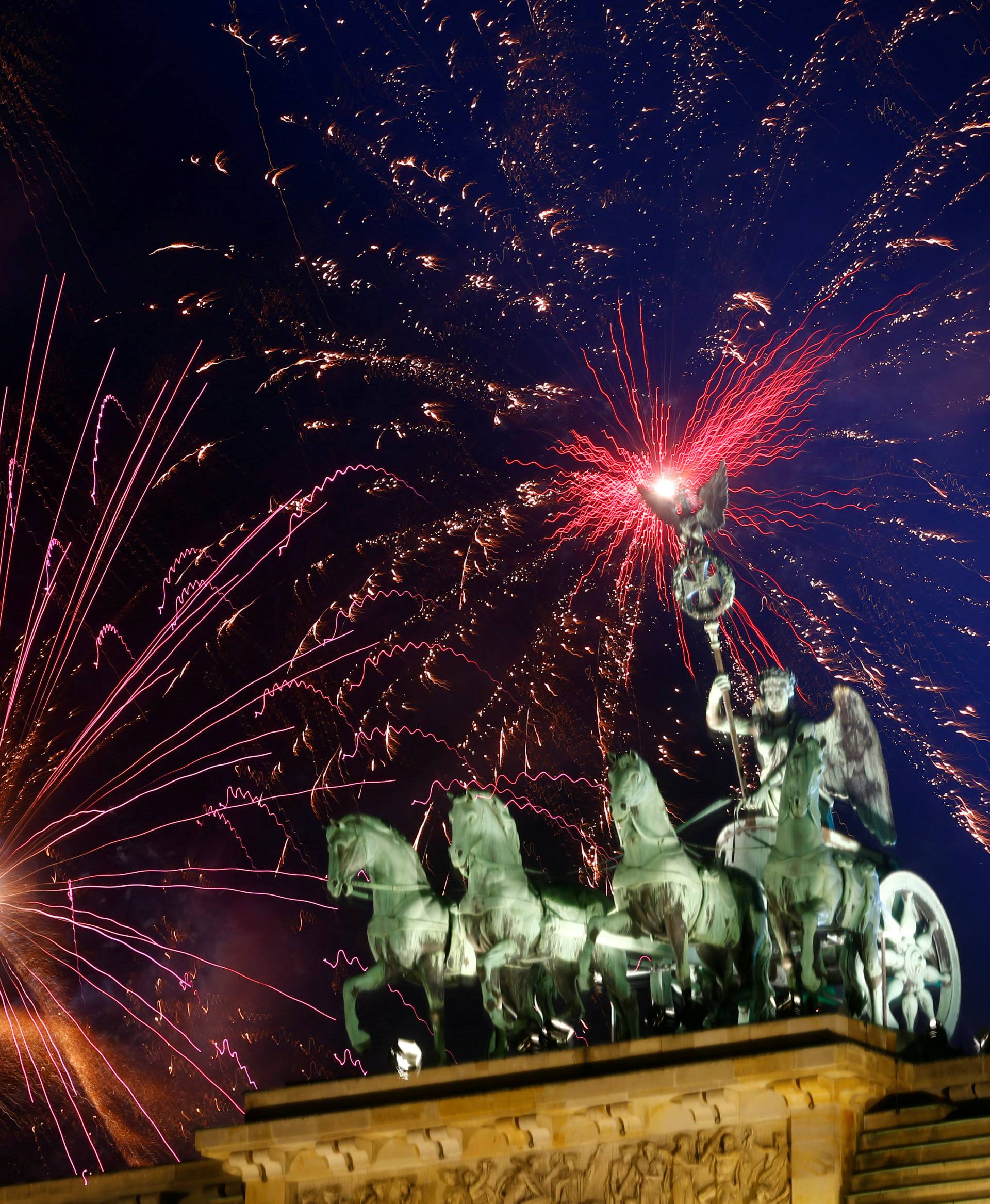 Fireworks explode next to the Quadriga sculpture atop the Brandenburg gate during New Year celebrations in Berlin