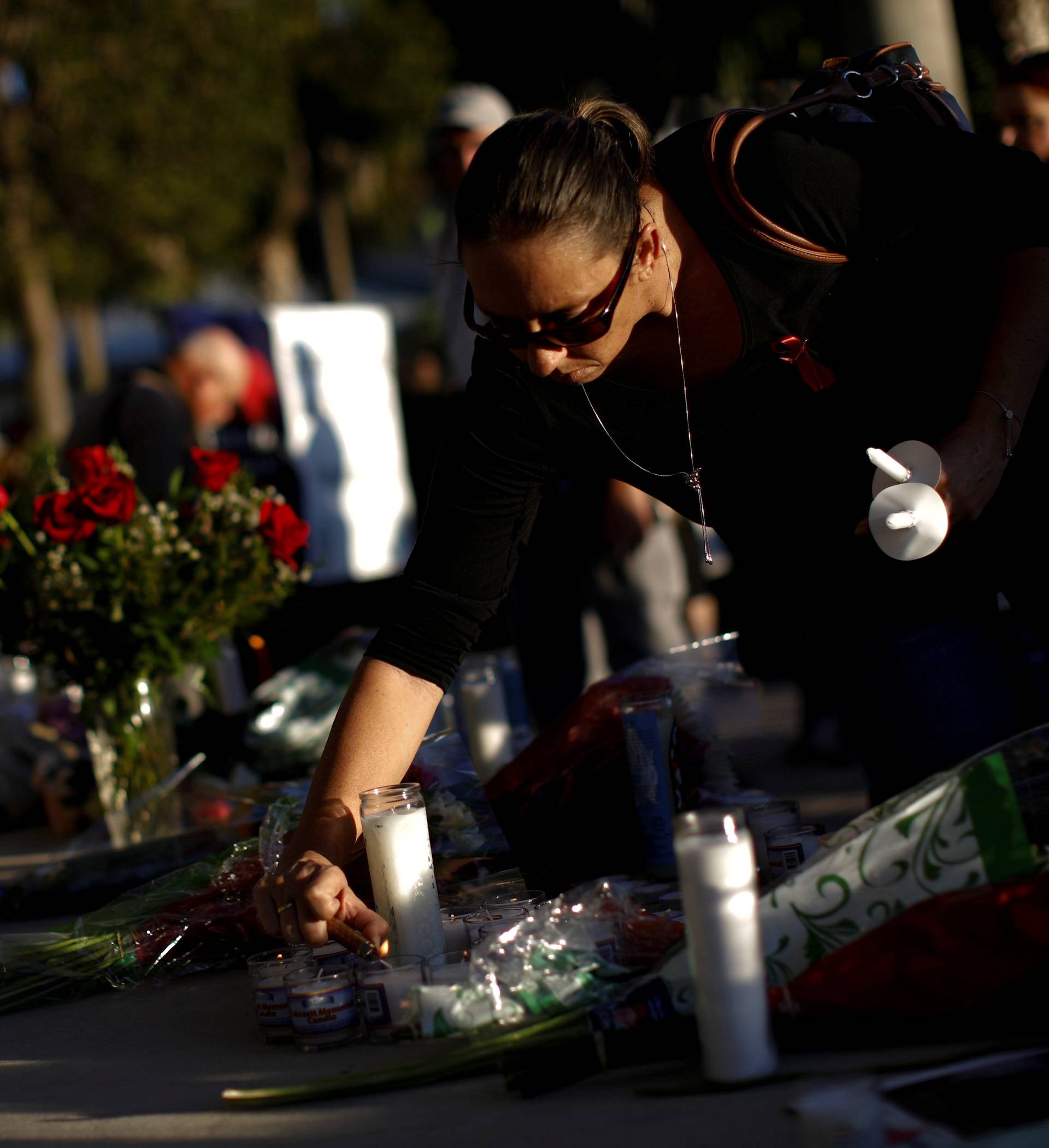 A woman lights a candle during a vigil for victims of yesterday's shooting at nearby Marjory Stoneman Douglas High School, in Parkland