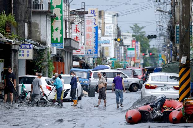People clean mud from a street following flooding brought by Super Typhoon Ragasa in Hualien,