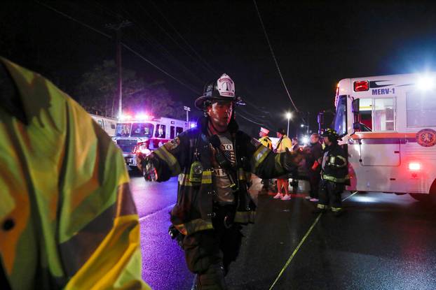 A firefighter clears the area while emergency responders  attend to a train that sits derailed near the community of New Hyde Park on Long Island in New York