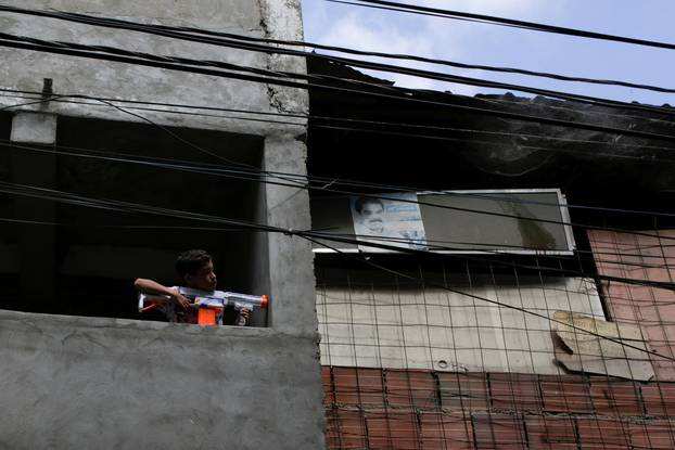 A boy plays with a toy gun at the slum of Petare in Caracas