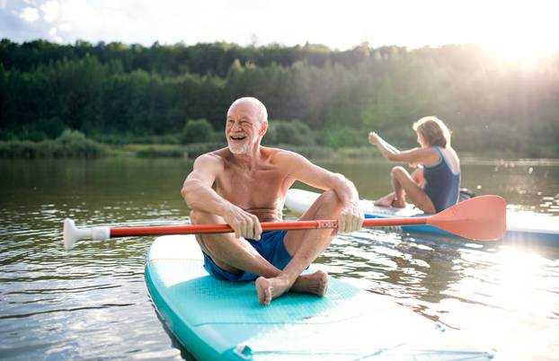 Senior,Couple,Paddleboarding,On,Lake,In,Summer.