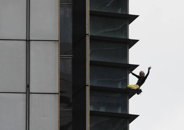 French climber Robert waves as he climbs down the 47-storey GT International Tower in Makati City