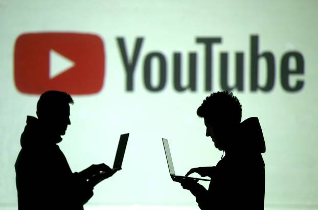 FILE PHOTO: FILE PHOTO: Silhouettes of mobile device users are seen next to a screen projection of Youtube logo in this picture illustration