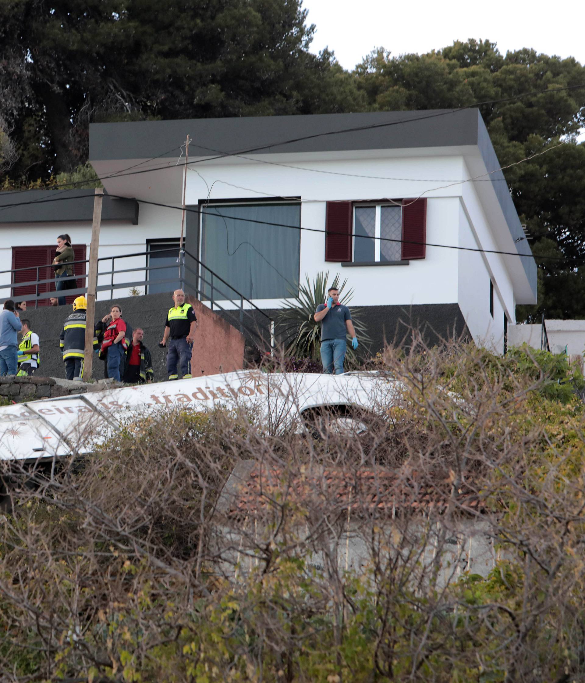 Rescue workers stand next to the wreckage of a bus after an accident in Canico