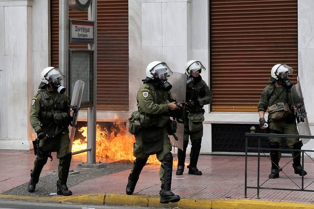 Riot police walk next to flames from a petrol bomb during a 24-hour general strike against the latest round of austerity in Athens