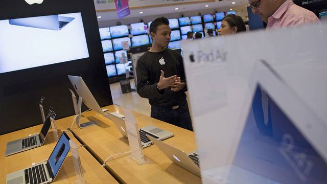 FILE PHOTO: An Apple salesperson speaks to customers at an electronics store in Mumbai
