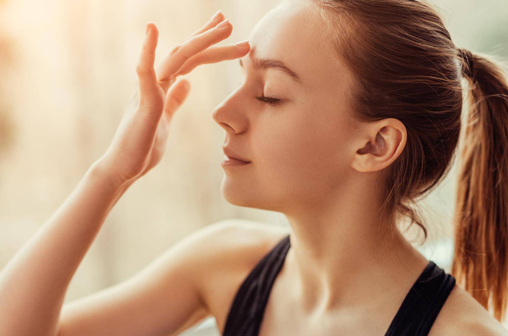 Young woman massaging third eye chakra