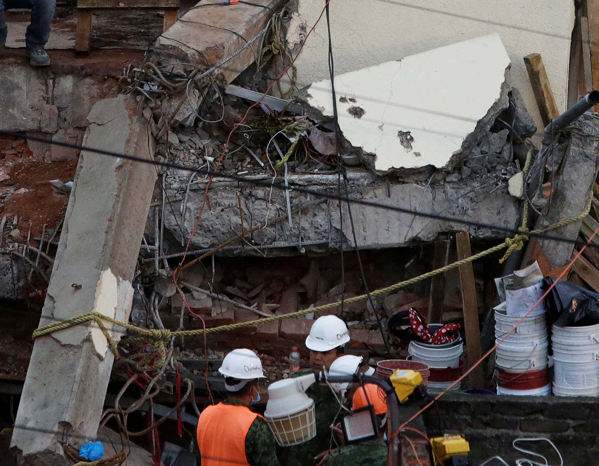 Rescue workers stand next to parts of a collapsed school building during a search for students at the Enrique Rebsamen school after an earthquake in Mexico City