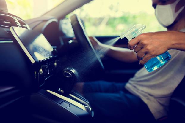 Hand of driver is spraying alcohol to gearshift stick to kill the Coronavirus (Covid 19) or contamination of germ.