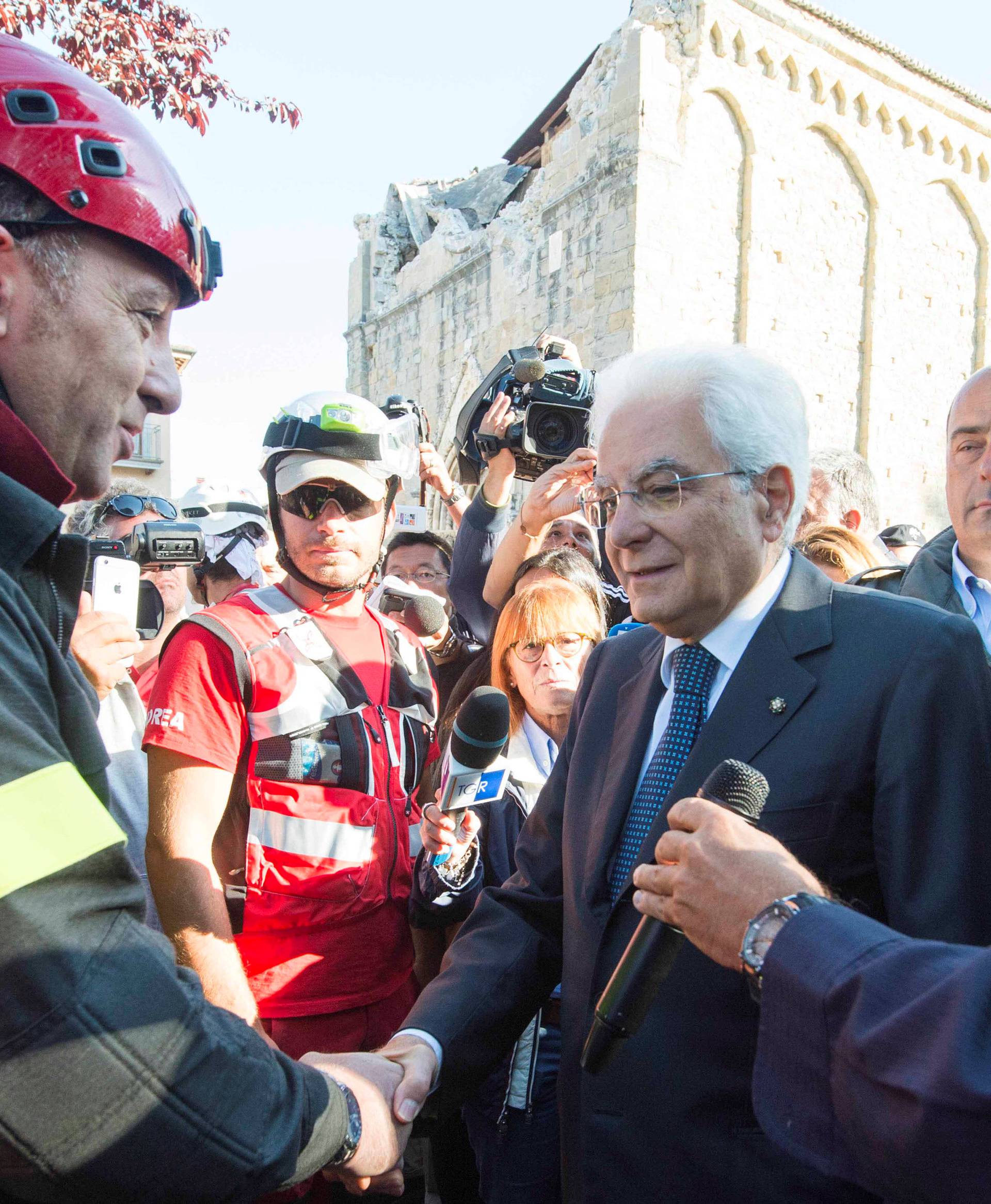 Italian President Sergio Mattarella shakes hands with a firefighter as he visits Amatrice after the earthquake in central Italy