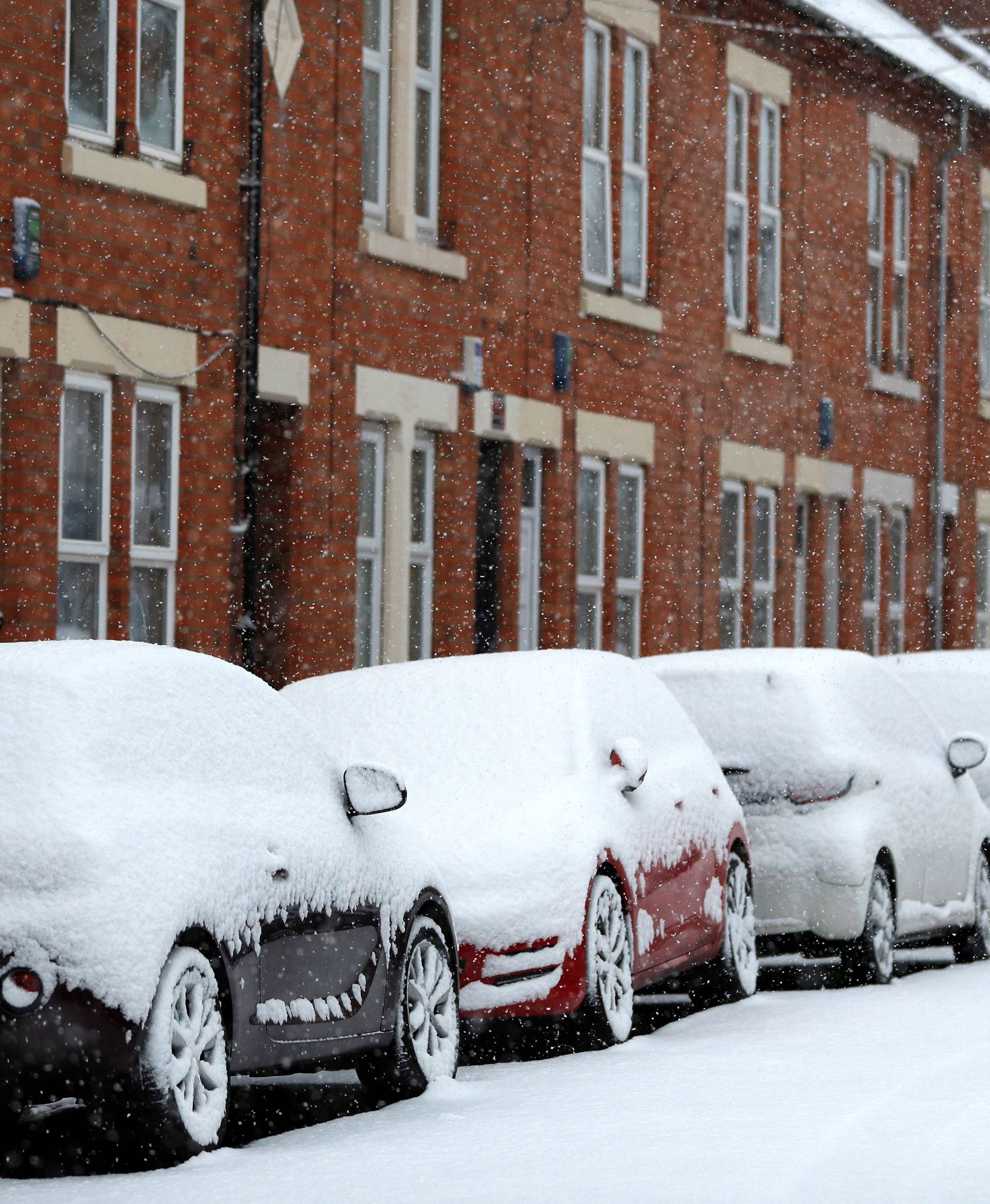 Snow piled high on parked cars is seen as the snow falls in Loughborough