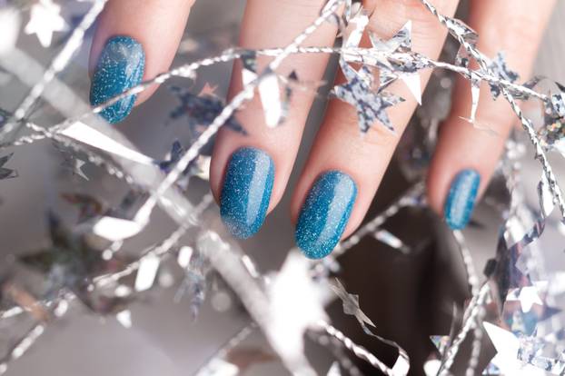 Hand with blue glitter nails with tinsel