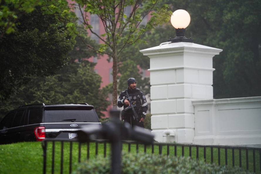 A U.S. Secret Service agent stands guard holding his weapon after alleged gunshots were heard nearby, at the White House in Washington