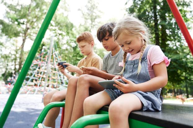 Group of kids using mobile phone at the playground 