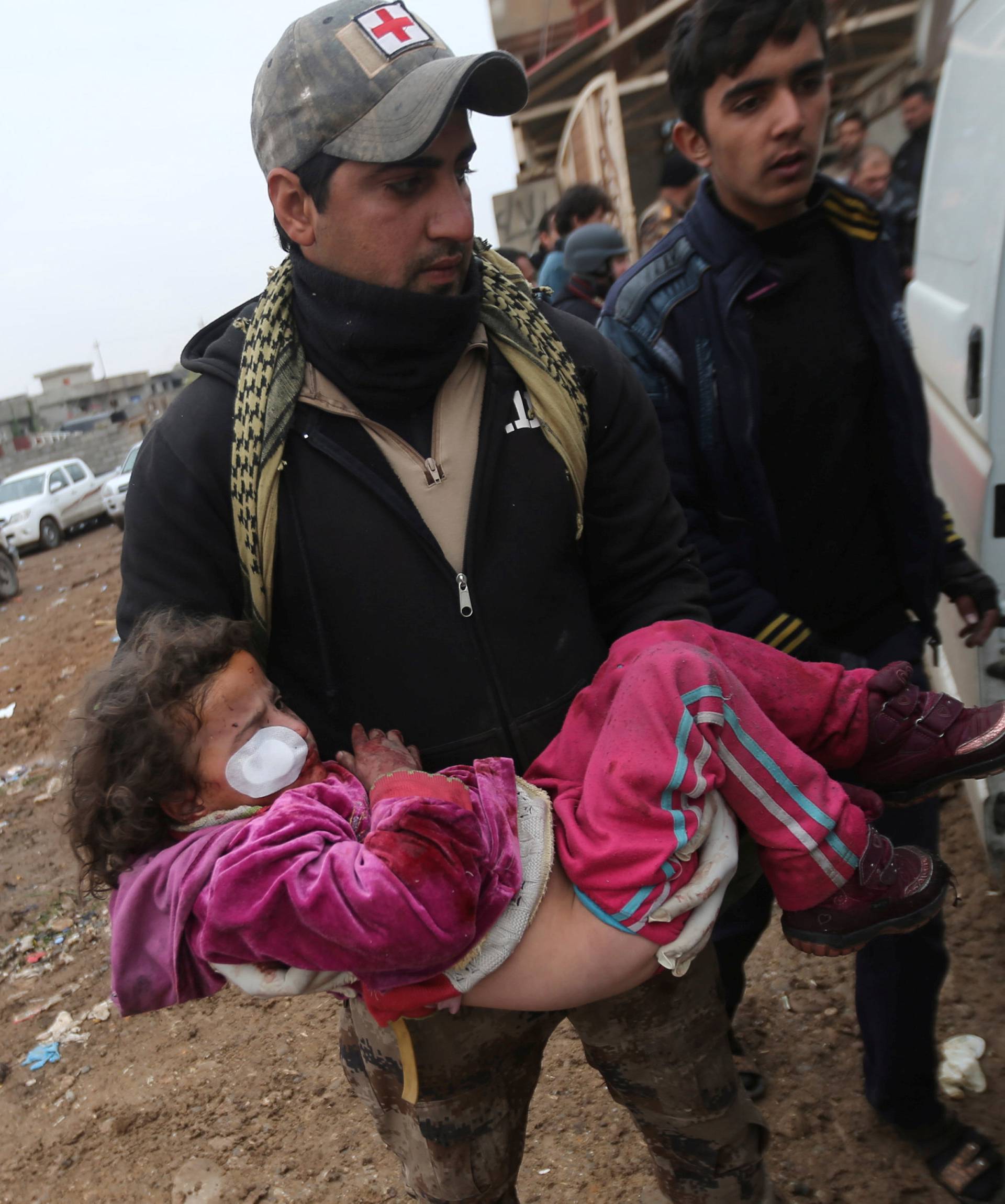 An Iraqi soldier carries a girl who was wounded during clashes in the Islamic State stronghold of Mosul into a field hospital in al-Samah neighborhood Iraq
