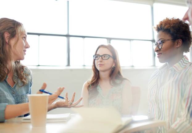 Unposed group of adult student in an open concept  class collaborating on their next project.