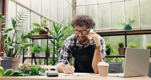 Happy,Caucasian,Businessman,Talking,On,Cellphone,While,Standing,In,Apron