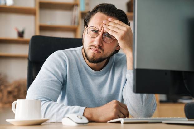 Image of brooding bearded programmer man working with computer