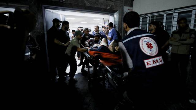 Injured people are assisted after Israeli air strike hit At Al-Ahli Hospital, according to Gaza Health Ministry