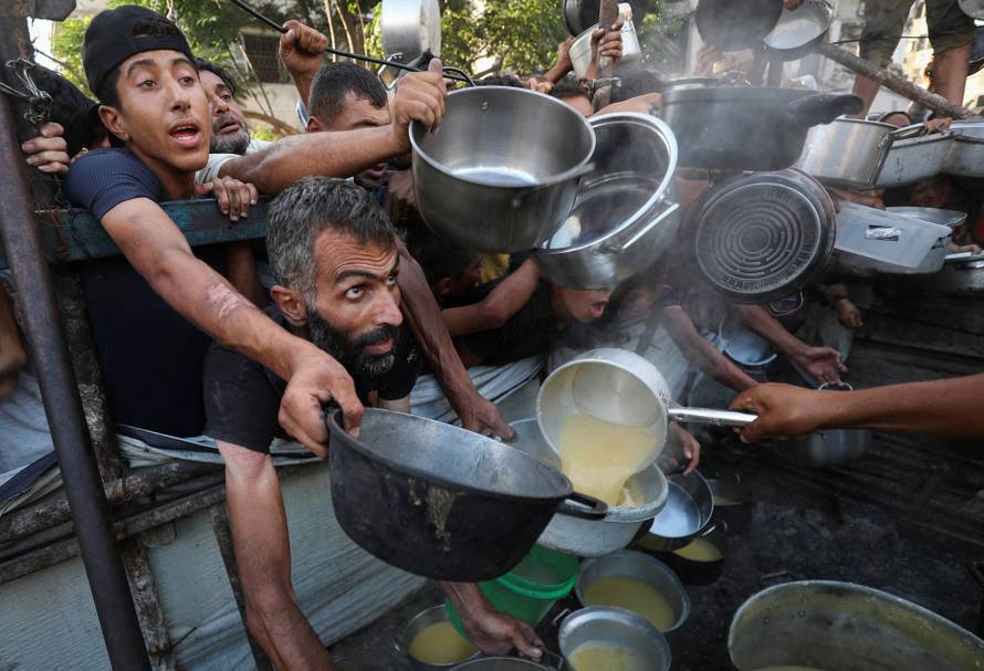 Palestinians receive food from a charity kitchen, amid a hunger crisis, in Gaza City