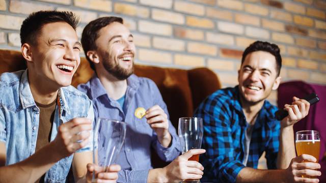 Friendship, sports and entertainment concept - happy male friends with beer watching tv at home.