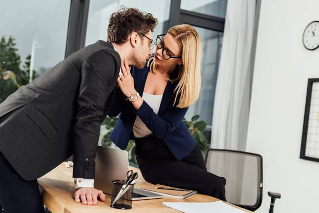 attractive young businesswoman flirting with business colleague at workplace in office
