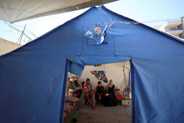 Displaced Palestinian man Nizar Bakron sits with his wife Amal and his children inside their tent, in Gaza City