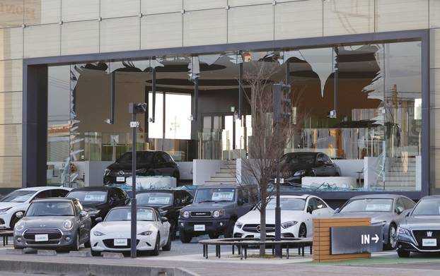 A car dealership’s window is broken following a strong earthquake in Koriyama