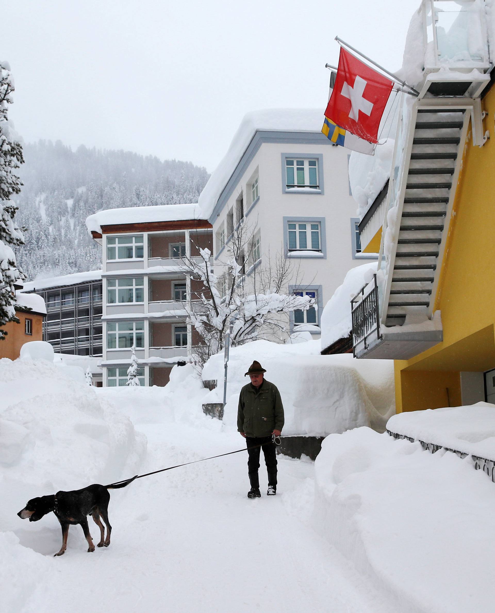 A man walks his dog after a snowfall ahead of the World Economic Forum (WEF) annual meeting in the Swiss Alps resort of Davos
