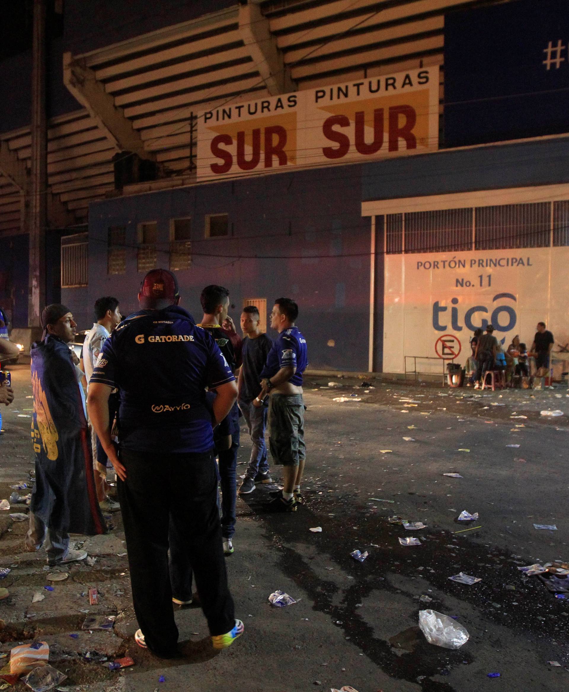 People stand outside at the National Stadium after an stampede when hundreds of fans tried to break past barricades in Tegucigalpa