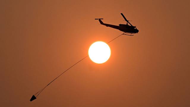 A water-bombing helicopter is seen flying past the sun near the town of Wallangarra in Queensland